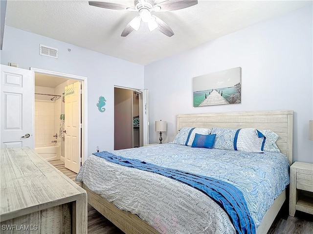 bedroom featuring hardwood / wood-style floors, a textured ceiling, ensuite bath, and ceiling fan