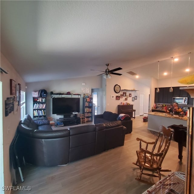 living room featuring ceiling fan, wood-type flooring, and lofted ceiling