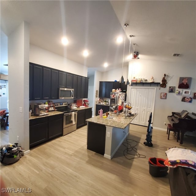 kitchen with pendant lighting, a breakfast bar, a center island with sink, light hardwood / wood-style flooring, and stainless steel appliances