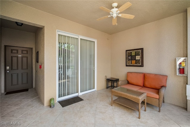 sitting room with ceiling fan, light tile patterned floors, and a textured ceiling