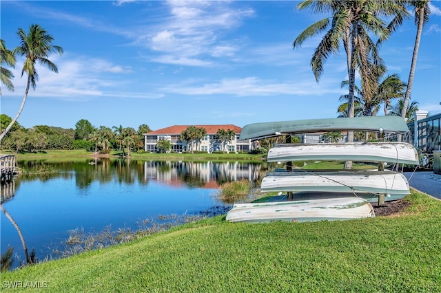 view of dock with a lawn and a water view