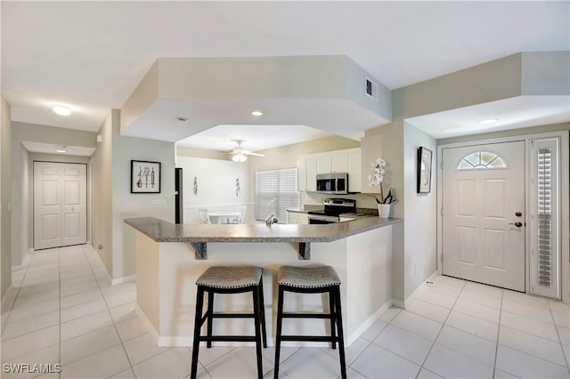 kitchen featuring white cabinets, kitchen peninsula, a breakfast bar area, and appliances with stainless steel finishes