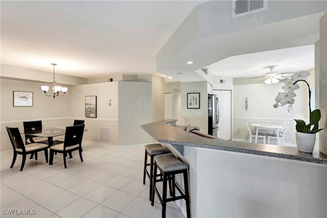 kitchen with stainless steel refrigerator, ceiling fan with notable chandelier, light tile patterned flooring, and decorative light fixtures