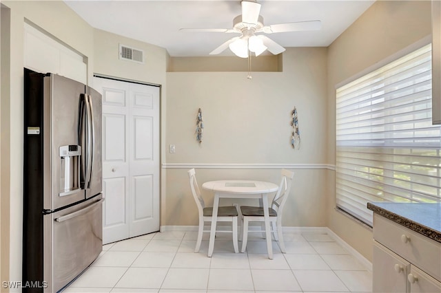 kitchen with stainless steel fridge, white cabinetry, ceiling fan, and light tile patterned flooring