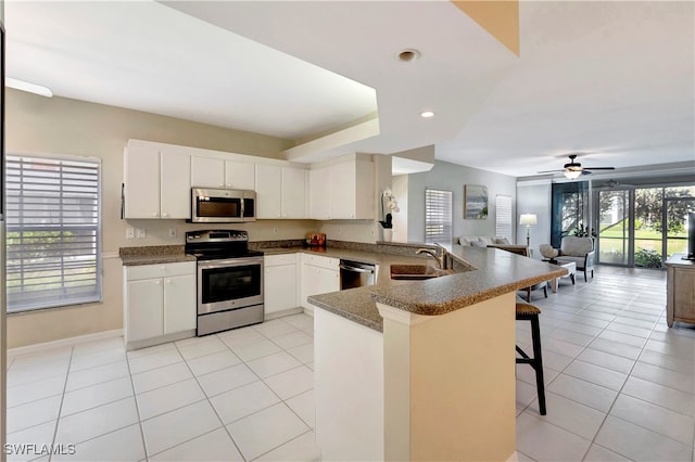 kitchen featuring white cabinetry, a healthy amount of sunlight, a kitchen breakfast bar, kitchen peninsula, and appliances with stainless steel finishes