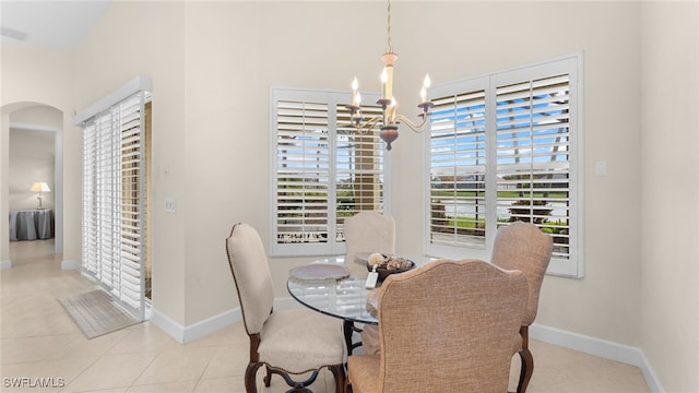 tiled dining room featuring baseboards and an inviting chandelier