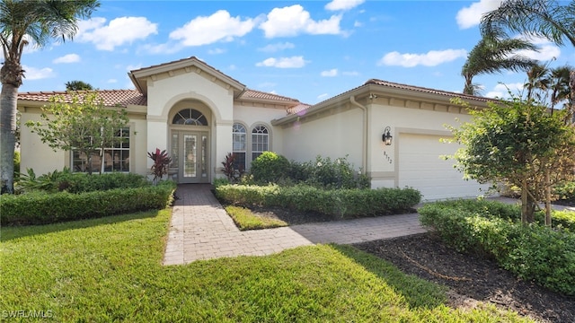 view of front of property with french doors, a garage, a tile roof, and stucco siding