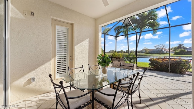 sunroom / solarium with a ceiling fan and a water view