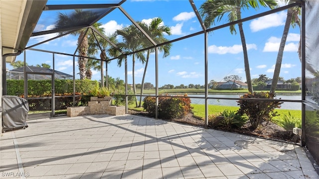 view of patio featuring glass enclosure and a water view