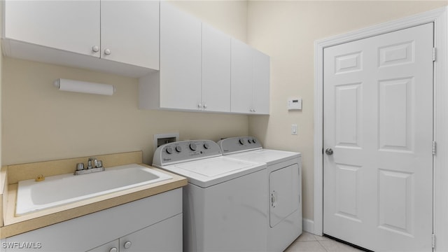 washroom featuring cabinet space, light tile patterned floors, washing machine and dryer, and a sink