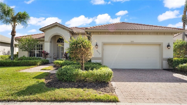 mediterranean / spanish-style house with a front yard, decorative driveway, a garage, and stucco siding