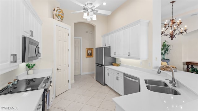 kitchen with a sink, arched walkways, appliances with stainless steel finishes, white cabinets, and light tile patterned floors