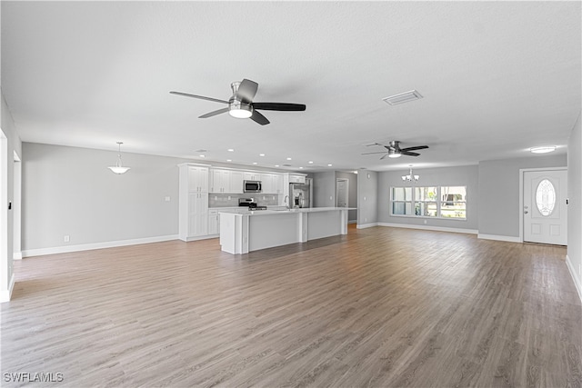 unfurnished living room with light hardwood / wood-style floors, ceiling fan, and sink