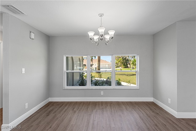 unfurnished dining area featuring dark hardwood / wood-style floors and an inviting chandelier