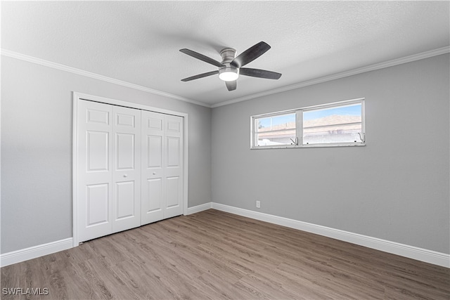 unfurnished bedroom featuring crown molding, ceiling fan, light wood-type flooring, a textured ceiling, and a closet