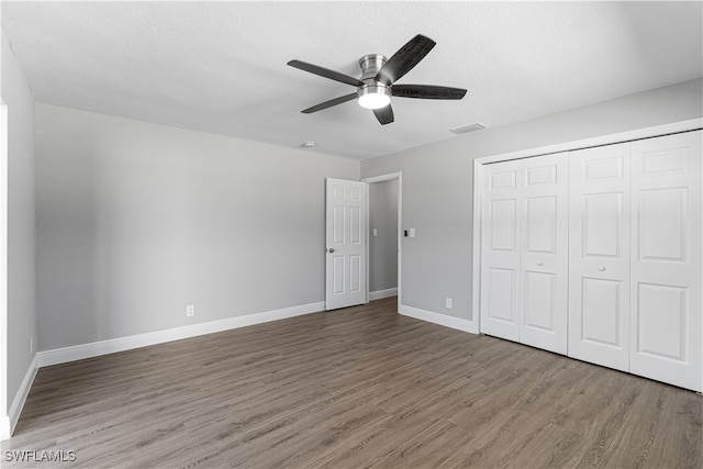 unfurnished bedroom with a textured ceiling, a closet, hardwood / wood-style flooring, and ceiling fan