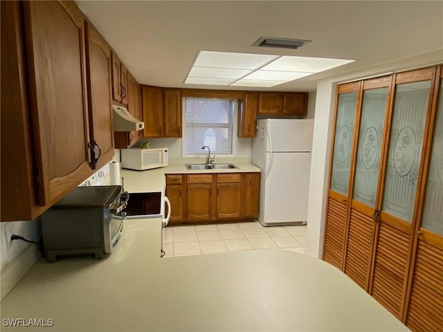 kitchen featuring light tile patterned floors, white appliances, and sink