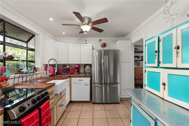 kitchen featuring stainless steel refrigerator, white cabinetry, sink, light tile patterned floors, and cooktop