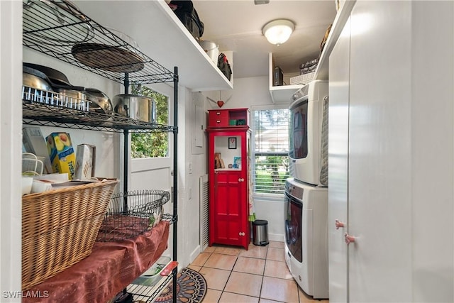 clothes washing area featuring plenty of natural light, stacked washer / drying machine, and light tile patterned floors