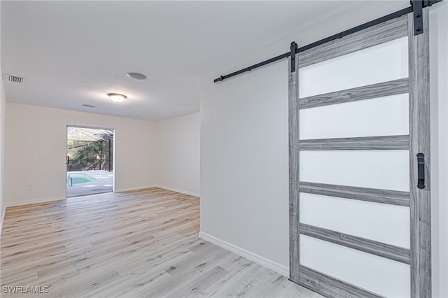 empty room featuring a barn door and light hardwood / wood-style flooring