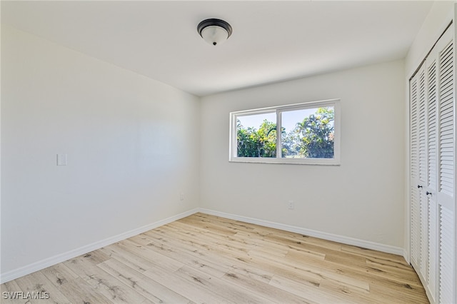 unfurnished bedroom with light hardwood / wood-style flooring and a closet