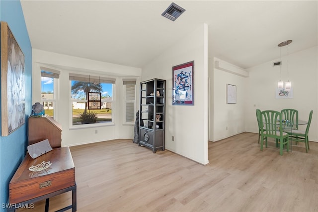 living area with a chandelier, light hardwood / wood-style floors, and vaulted ceiling