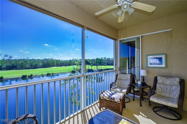 sunroom featuring ceiling fan and a water view