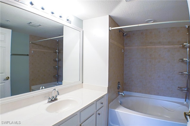 bathroom featuring vanity, a textured ceiling, and tiled shower / bath