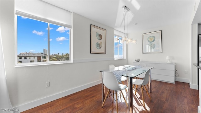 dining space with dark wood-type flooring and a notable chandelier