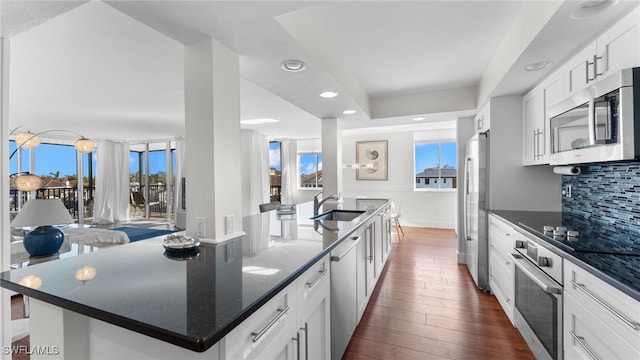 kitchen featuring a center island with sink, white cabinetry, stainless steel appliances, and a wealth of natural light