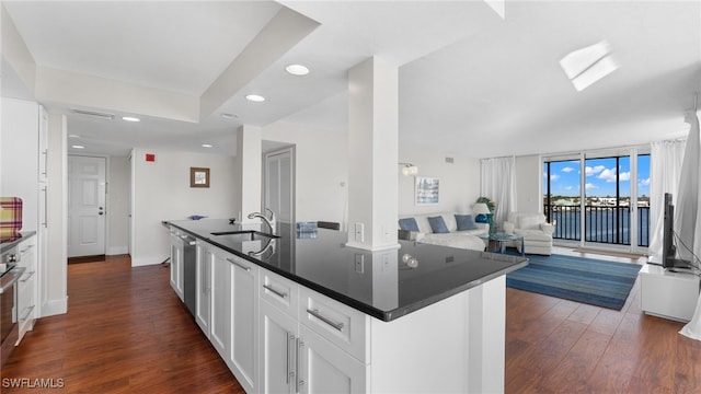 kitchen with dishwasher, sink, dark hardwood / wood-style floors, a kitchen island with sink, and white cabinets