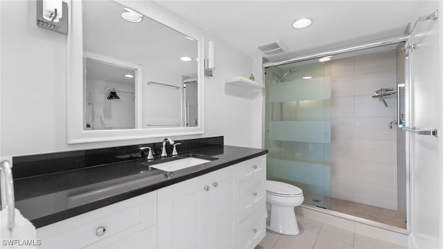 bathroom featuring tile patterned floors, vanity, toilet, and a shower with door