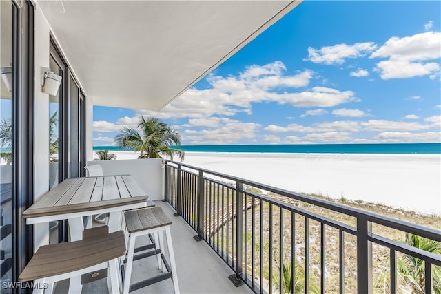 balcony featuring a water view and a beach view