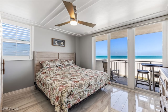 bedroom with access to exterior, ceiling fan, a water view, and a view of the beach