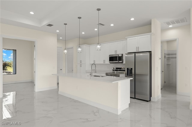 kitchen with stainless steel appliances, a kitchen island with sink, sink, pendant lighting, and white cabinetry