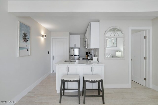 kitchen featuring a kitchen bar, white cabinetry, and sink