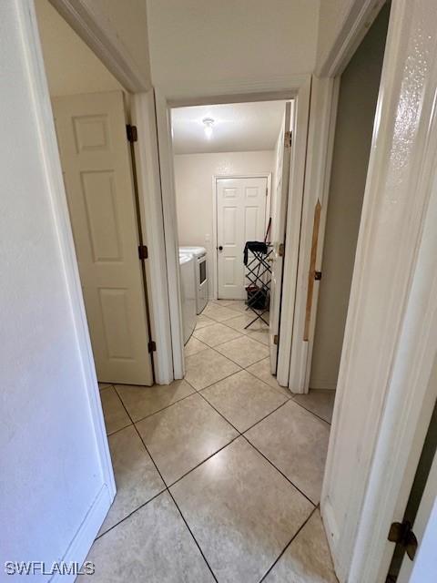 hall with independent washer and dryer and light tile patterned flooring