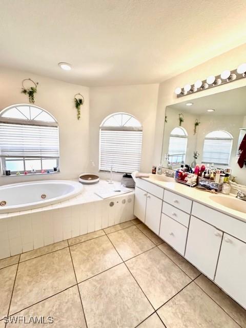 bathroom featuring vanity, tile patterned floors, and tiled tub