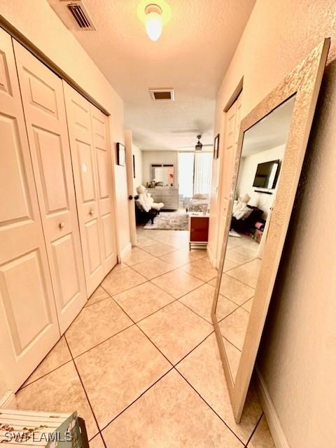 hall featuring light tile patterned flooring and a textured ceiling