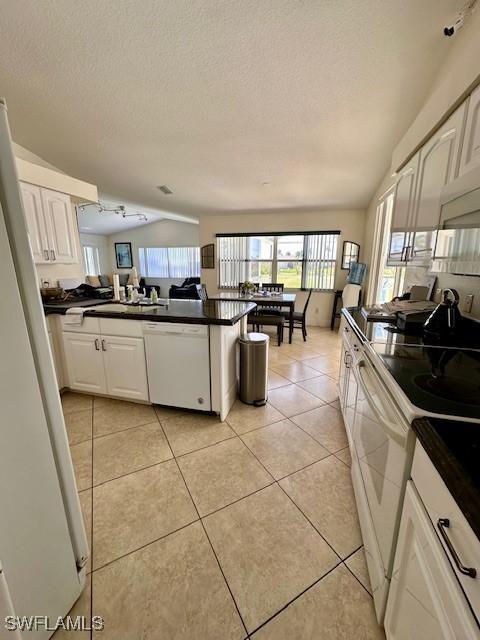 kitchen with white cabinets, white appliances, a textured ceiling, and light tile patterned floors