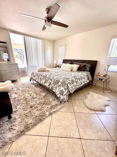 bedroom featuring tile patterned flooring, ceiling fan, a textured ceiling, and multiple windows