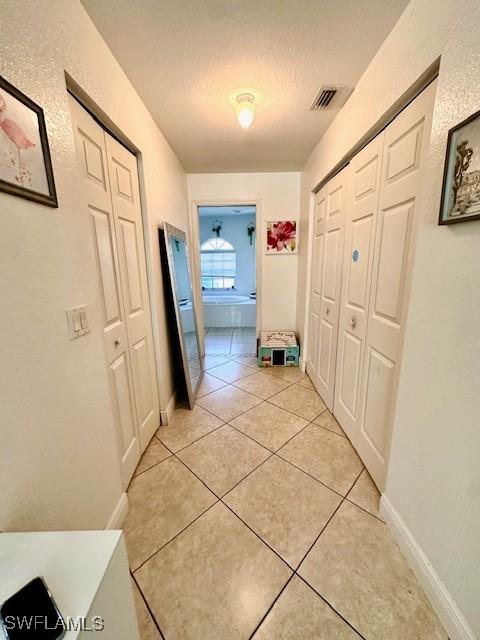 hallway featuring light tile patterned floors and a textured ceiling