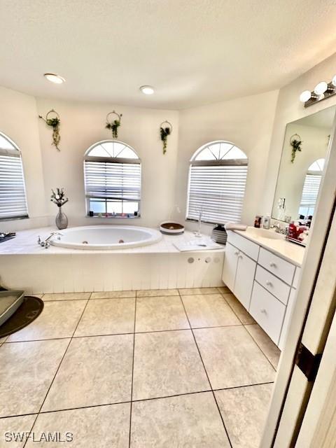 bathroom with tile patterned flooring, vanity, a bath, and a wealth of natural light