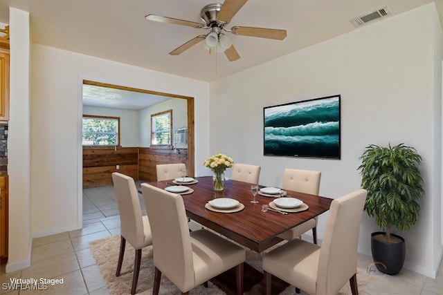 tiled dining room with ceiling fan and wooden walls