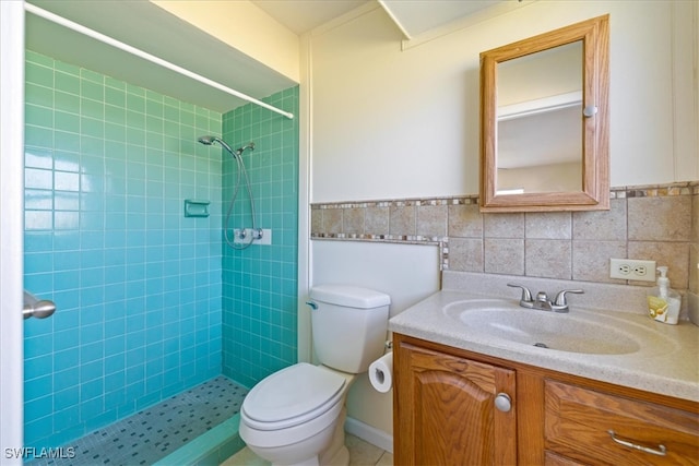 bathroom with toilet, a tile shower, tile walls, and vanity