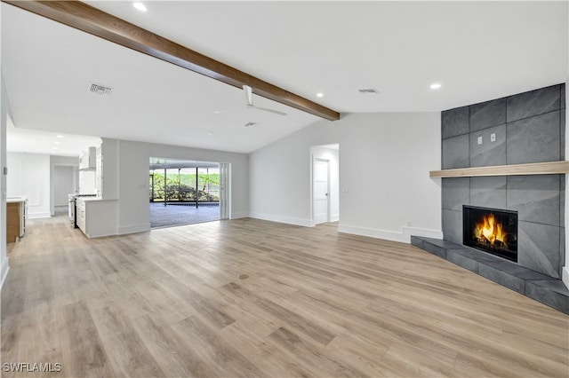 unfurnished living room featuring lofted ceiling with beams, light hardwood / wood-style floors, and a tiled fireplace