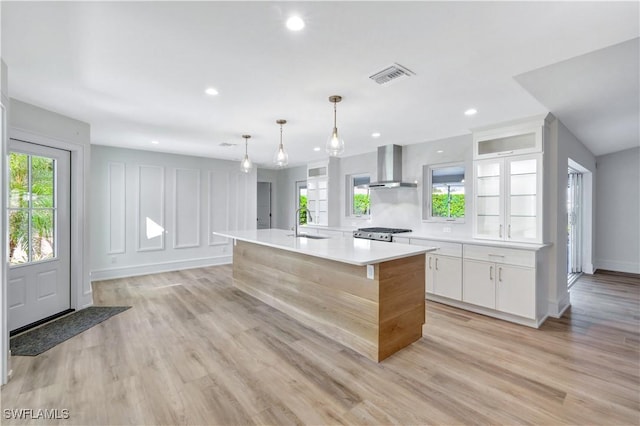 381 Norwood Ct, Fort Myers, FL 33919 - kitchen with wall chimney exhaust hood, white cabinets, light countertops, range, and an island with sink