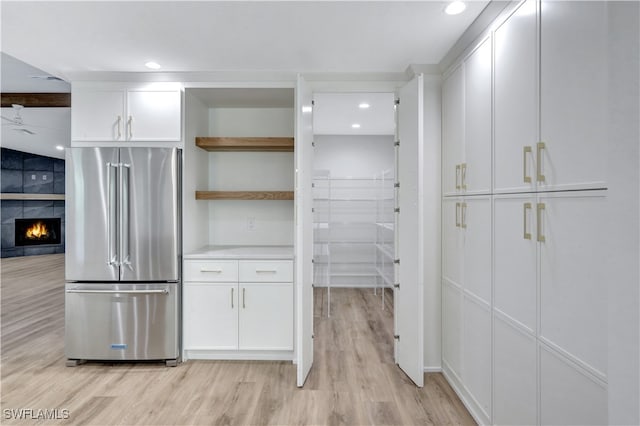 kitchen featuring a tile fireplace, light hardwood / wood-style floors, white cabinetry, and high quality fridge