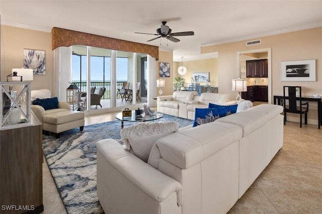 tiled living room with ceiling fan and crown molding