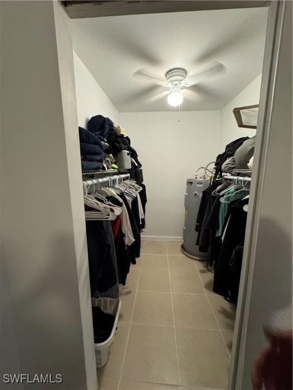 spacious closet featuring ceiling fan, light tile patterned flooring, and water heater